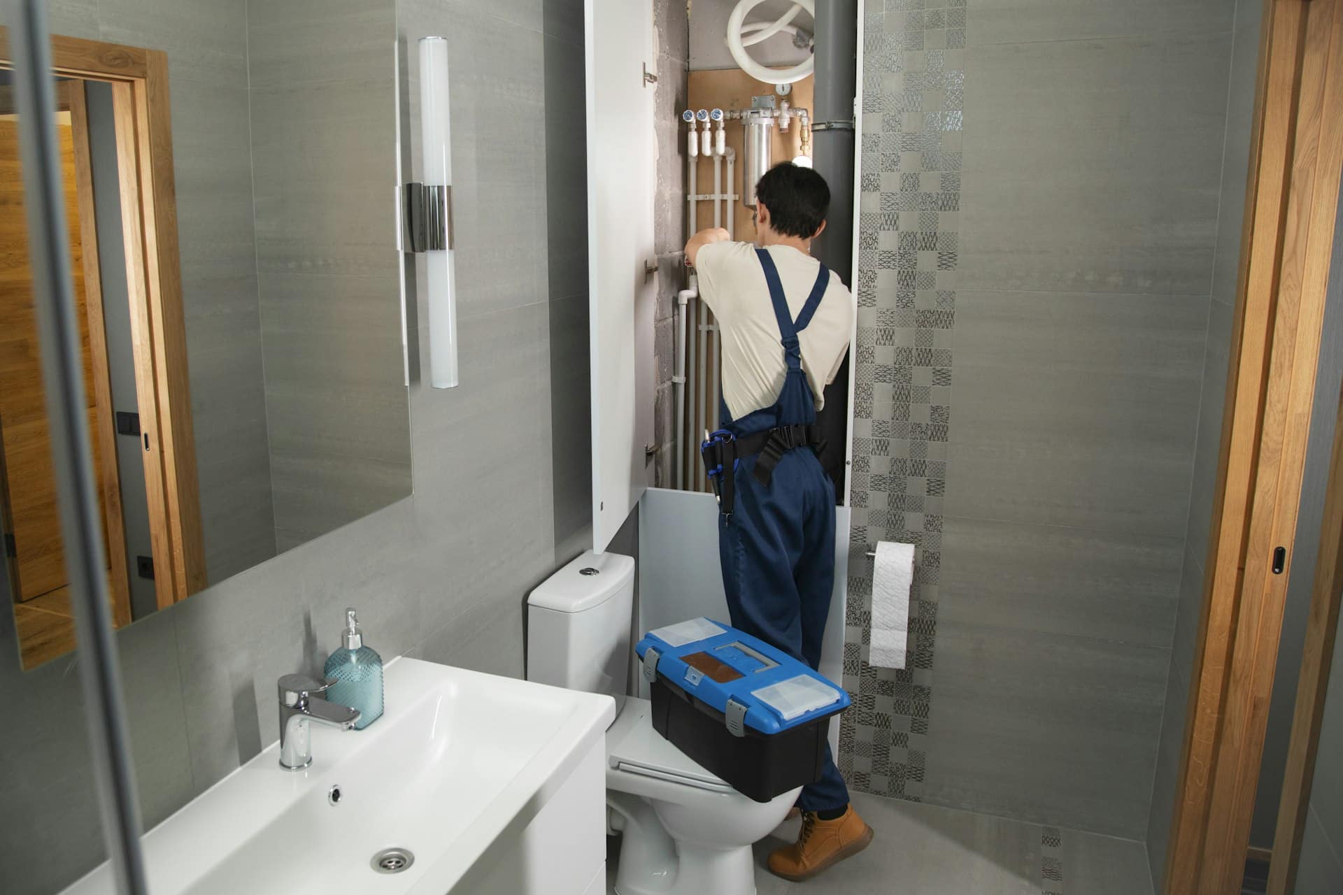 Handwerker prüft Rohrleitungen im Bad, um die Ursache eines Wasserschadens zu finden